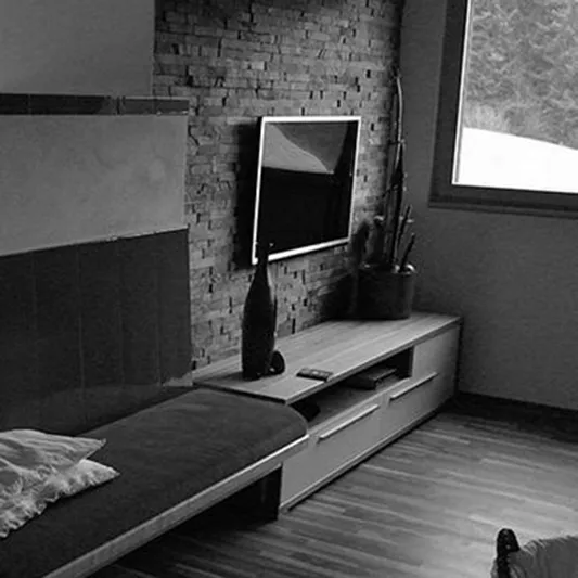 Innenraumdetail eines Wohnprojekts mit Holzboden und Natursteinwand
